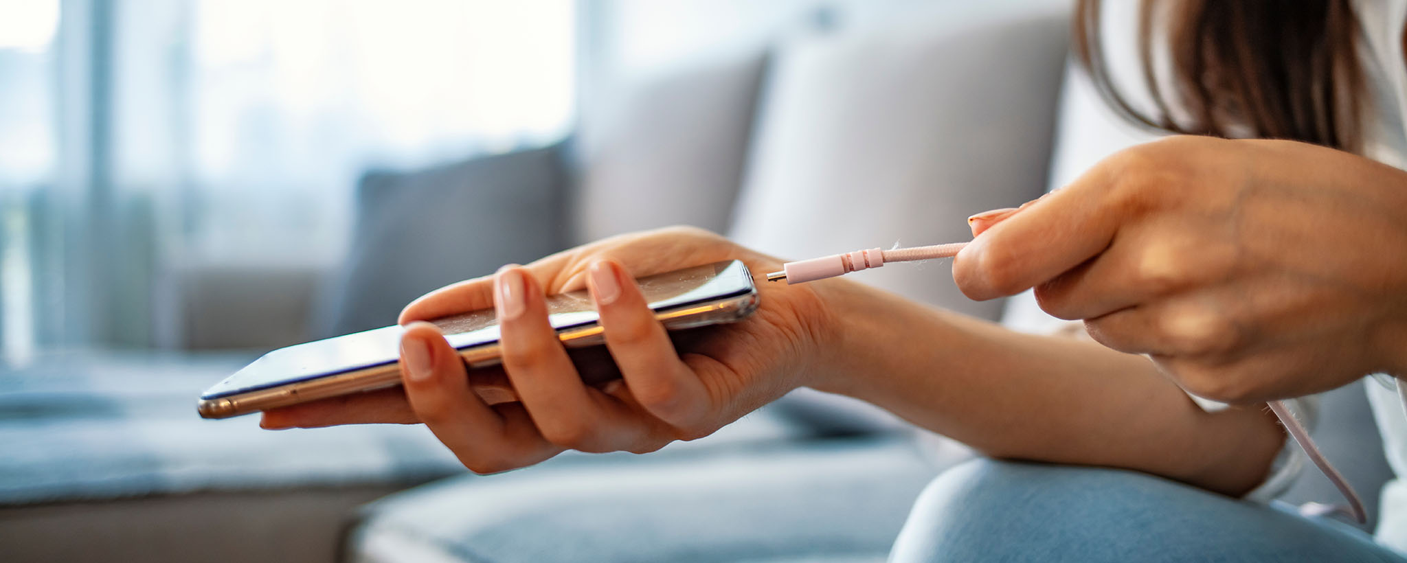 Las manos de una mujer enchufando un cargador de teléfono
